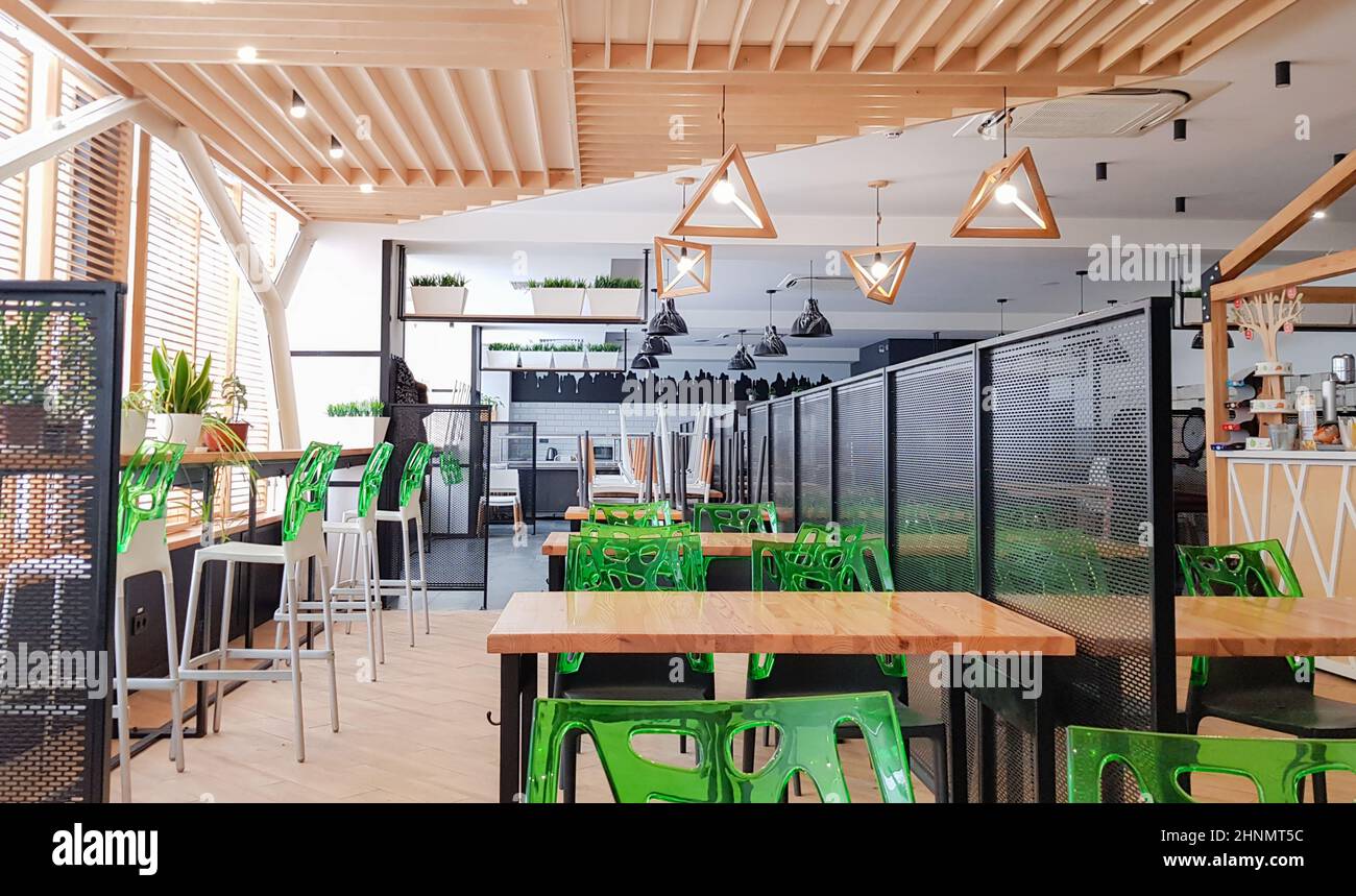 Cafétéria, pas de personnes salle à manger avec des tables en bois et des chaises vertes. Intérieur avec éléments en bois et en métal. Salle à manger moderne avec éclairage par fenêtre. Ukraine, Kiev - 19 février 2021 Banque D'Images