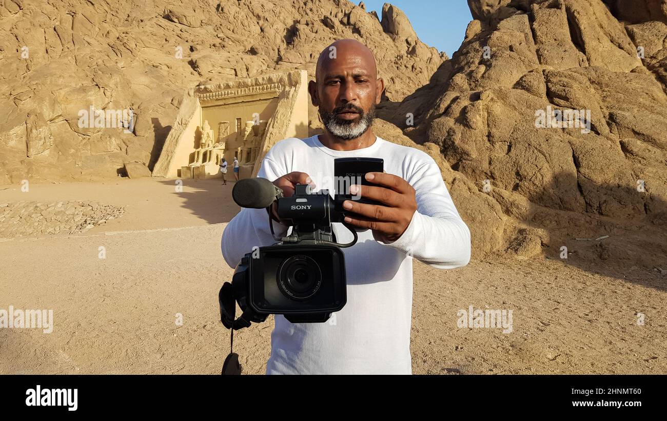 Égypte, Charm El-Cheikh - 30 mars 2020. Un vidéaste égyptien noir adulte avec un caméscope Sony dans ses mains tue des touristes sur fond de désert à Charm El Sheikh. Banque D'Images