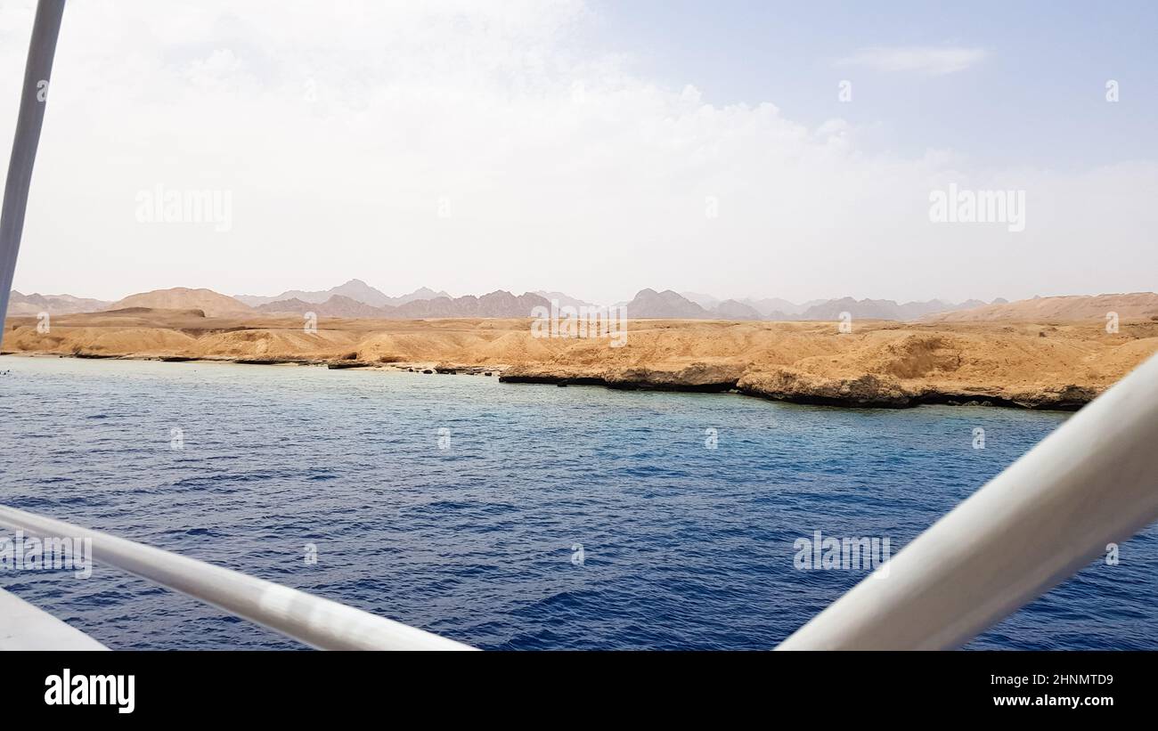 Belle vue depuis le pont d'un bateau de croisière dans la mer Rouge en Egypte. Paysage de la côte rocheuse égyptienne avec un yacht. Partie du navire sur fond de désert et de mer. Banque D'Images