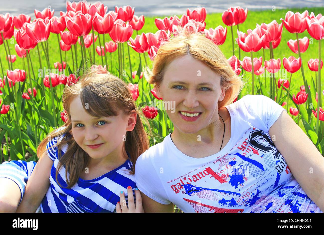 Mère avec fille souriante près du lit de fleurs de tulipe. Vacances en famille Banque D'Images