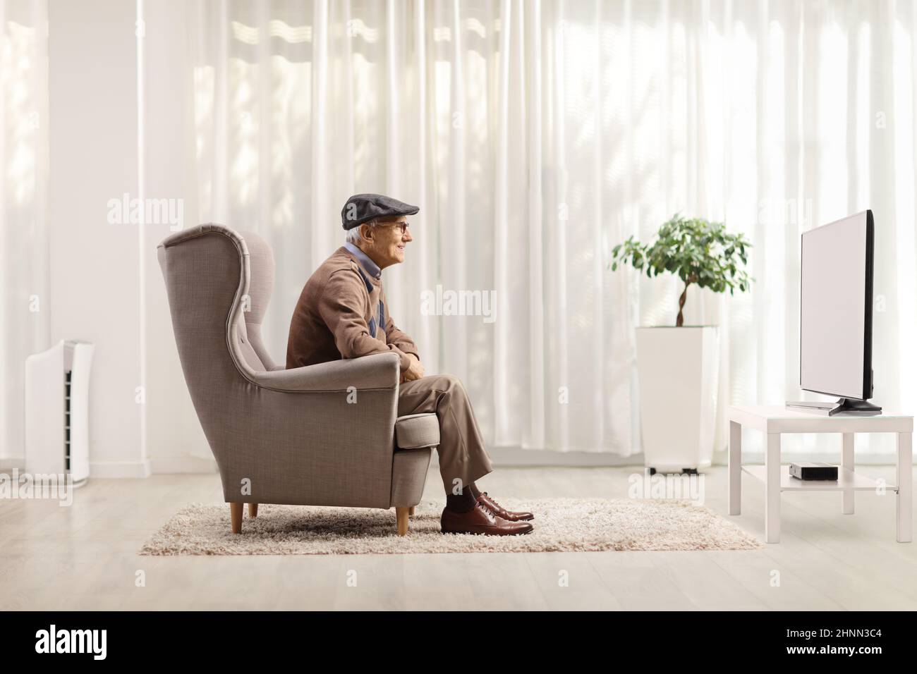 Photo d'un homme âgé assis dans un fauteuil et regardant la télévision à la maison Banque D'Images