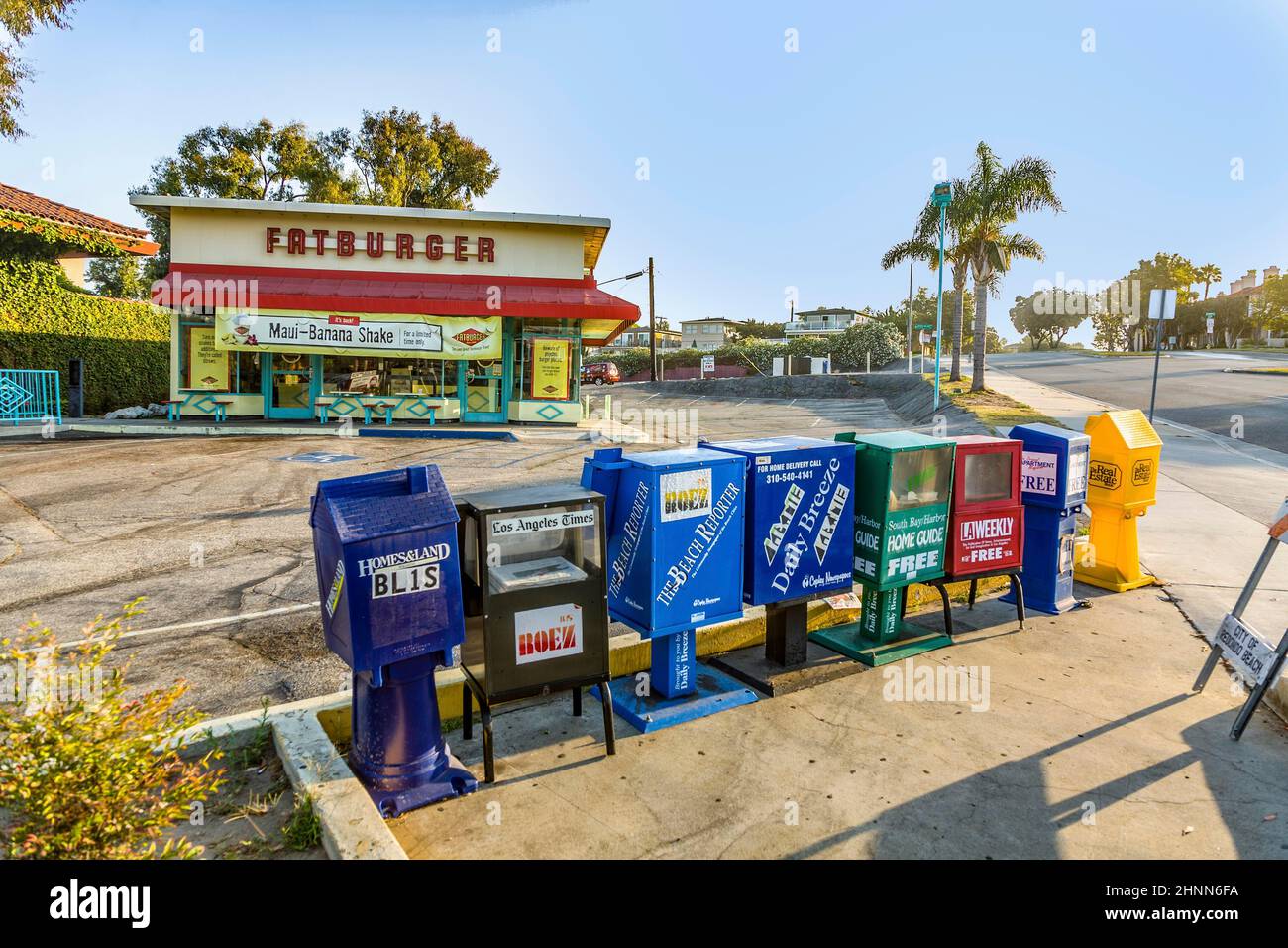 Boîtes de journaux en libre service à Los Angeles et restaurant fastfood en arrière-plan Banque D'Images