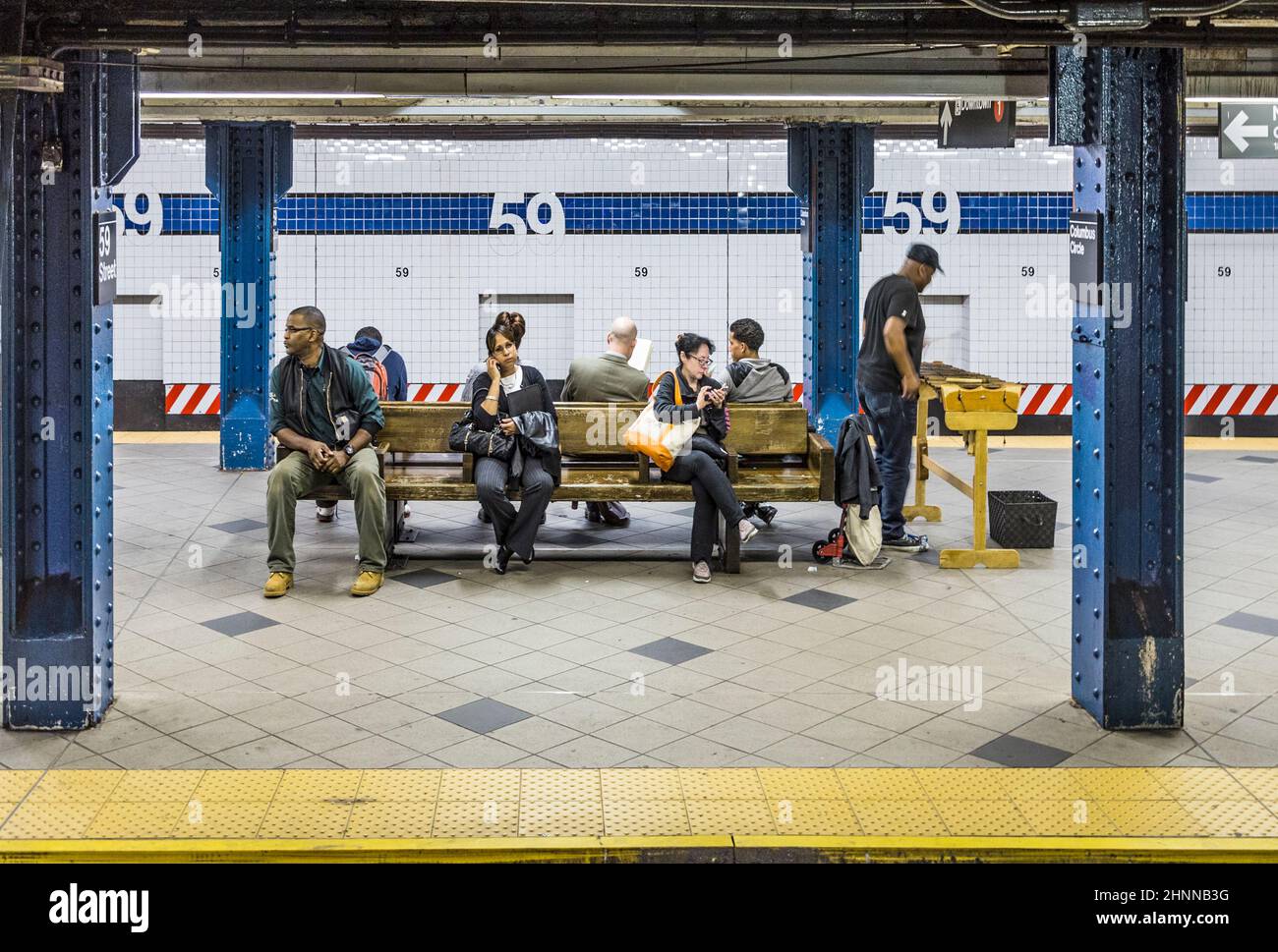 Les gens attendent à un banc pour le prochain métro à la station 59th rue à New York Banque D'Images