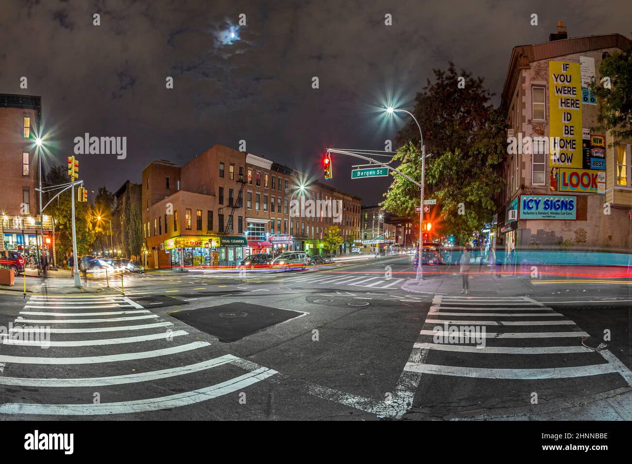 Vue de nuit pour traverser la rue bergen à New York avec des voitures et des gens flous et la lune au ciel. Banque D'Images