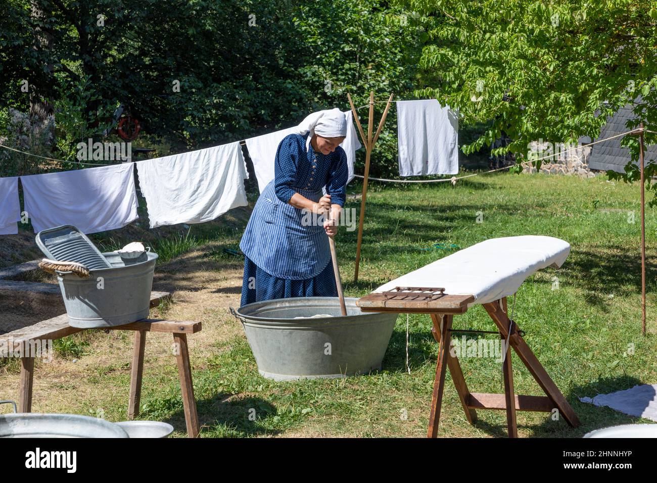 femme en costume traditionnel nettoie le linge de la vieille manière traditionnelle Banque D'Images