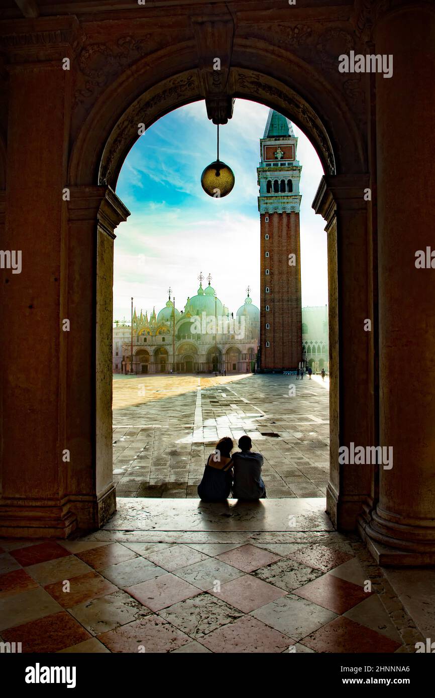 Couple regarde le lever du soleil sur la place Saint-Marc avec vue sur la basilique de San Marco dans la lumière du matin Banque D'Images