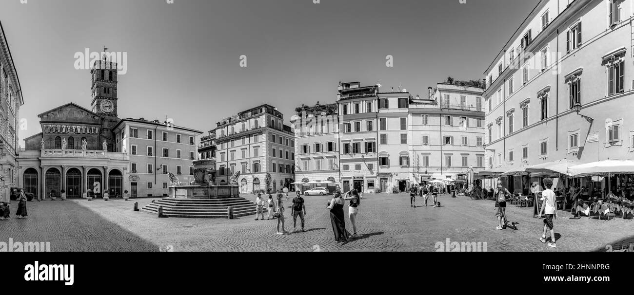 Les personnes à la Piazza di Santa maria avec fontaine et église Santa Maria au soleil de midi apprécient le lieu pittoresque à Rome, Italie Banque D'Images