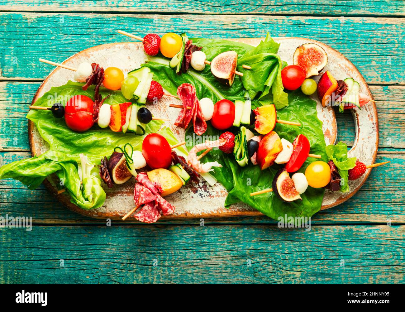 Buffet d'hors-d'œuvre de crevettes, jamon, fruits et légumes sur brochettes en bois Banque D'Images