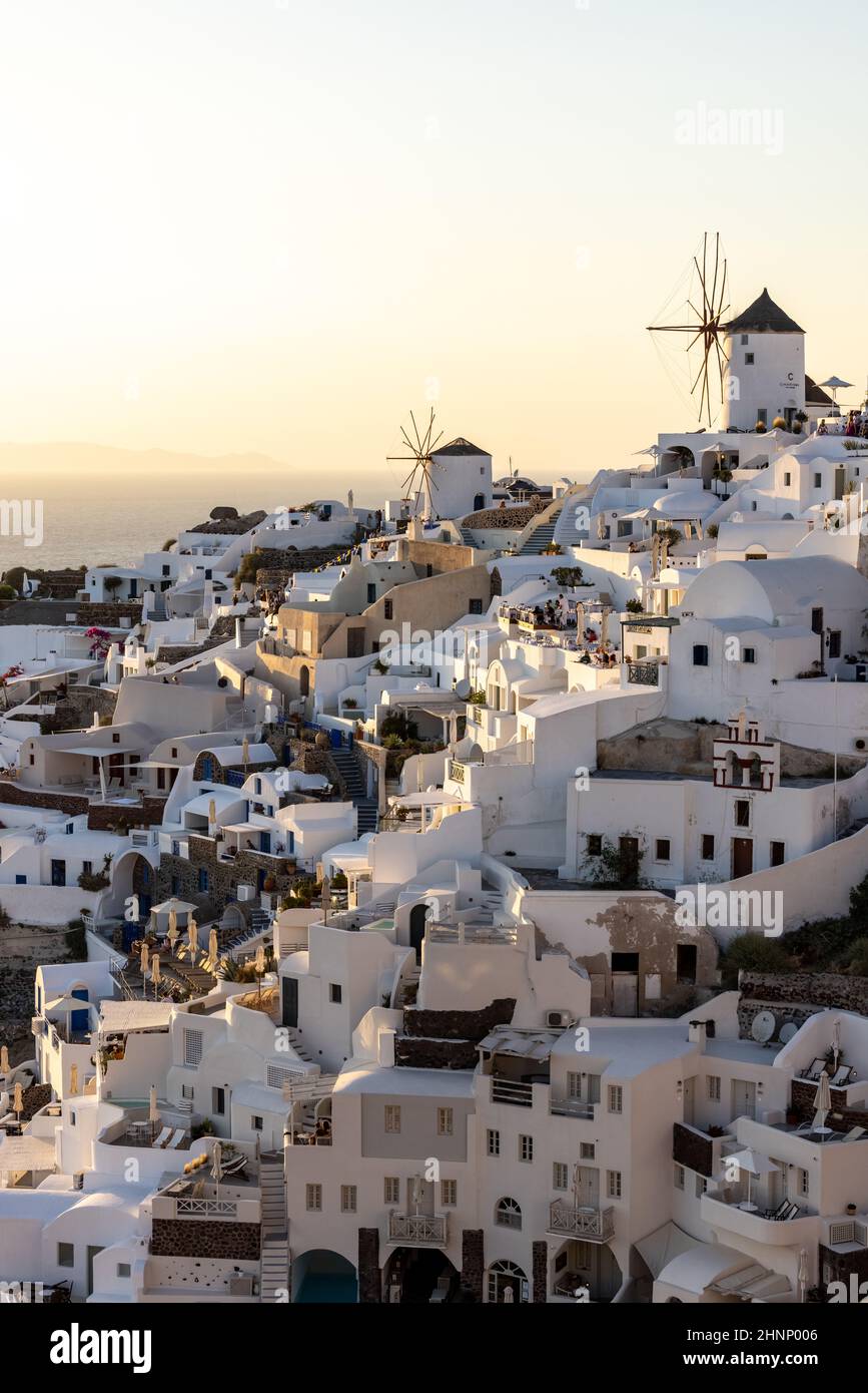 Maisons et moulins à vent blanchis à la chaux à Oia dans les rayons chauds du coucher du soleil sur l'île de Santorini. Grèce Banque D'Images