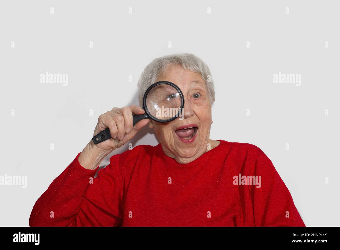 portrait d'une femme âgée regardant à travers une loupe sur blanc Banque D'Images