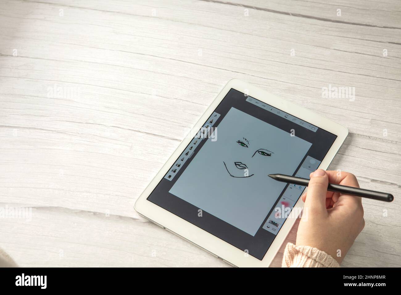 Jeune créateur tenant le stylet dessin à l'écran de tablette numérique sur un bureau en bois avec espace de copie, vue de dessus d'art numérique moderne Banque D'Images