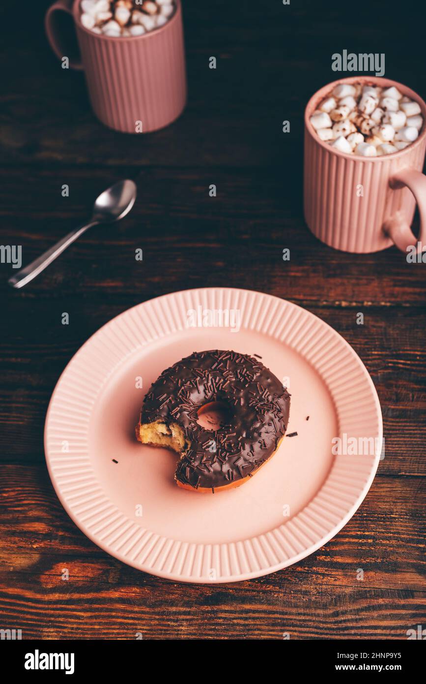 Chocolat maison Donut avec une bouchée et des tasses de chocolat chaud avec Marshmallow sur une surface en bois rustique Banque D'Images