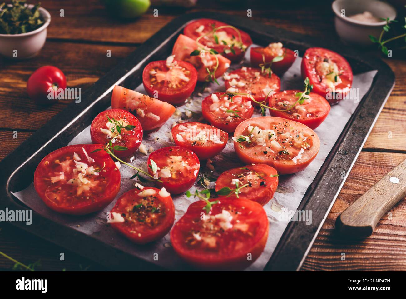 Préparation de conserves de tomates dans l'huile d'olive avec thym et Ail sur plat à pâtisserie Banque D'Images