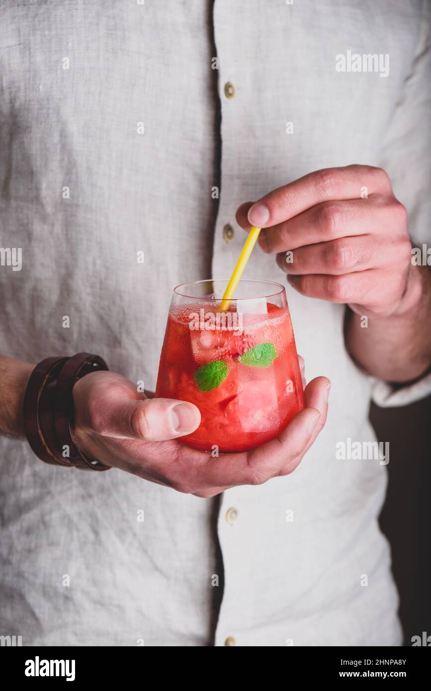 Verre de cocktail de pastèque avec gin et soda dans les mains Banque D'Images