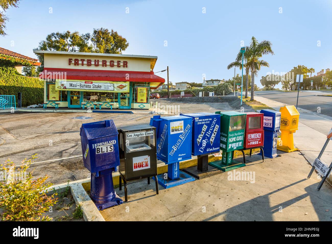 Boîtes de journaux en libre service à Los Angeles et restaurant fastfood en arrière-plan Banque D'Images