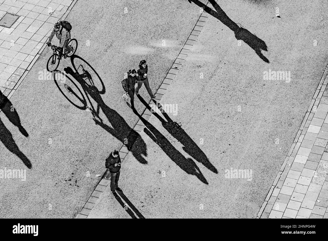 les gens qui marchent dans la rue avec de longues ombres Banque D'Images