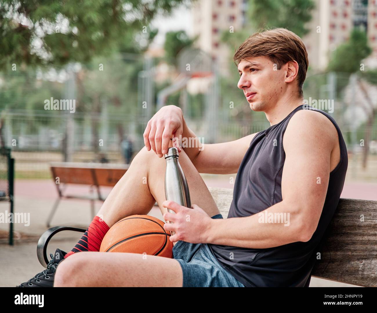 un joueur de basket-ball qui se repose. un sportif qui tient une bouteille d'eau. Banque D'Images