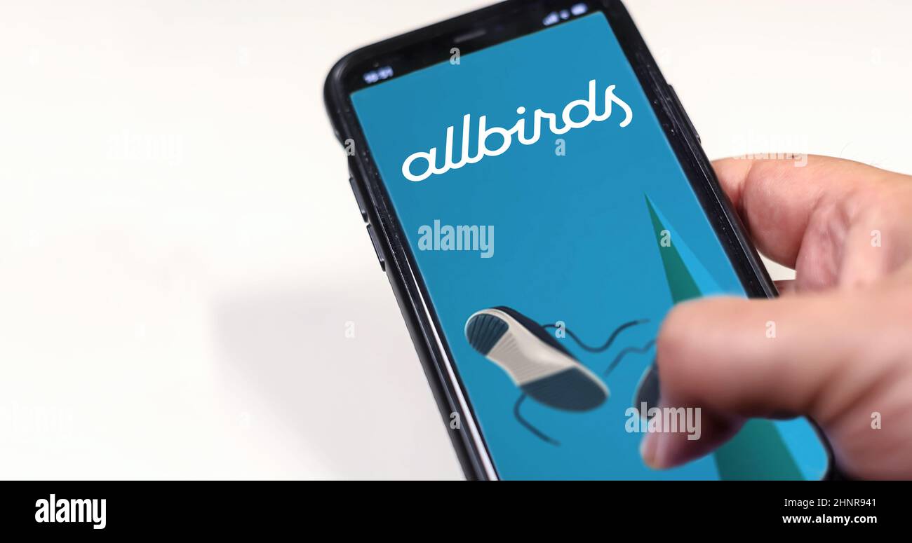 Main tenant un téléphone avec l'application mobile Allbirds sur l'écran isolé sur un fond blanc Banque D'Images