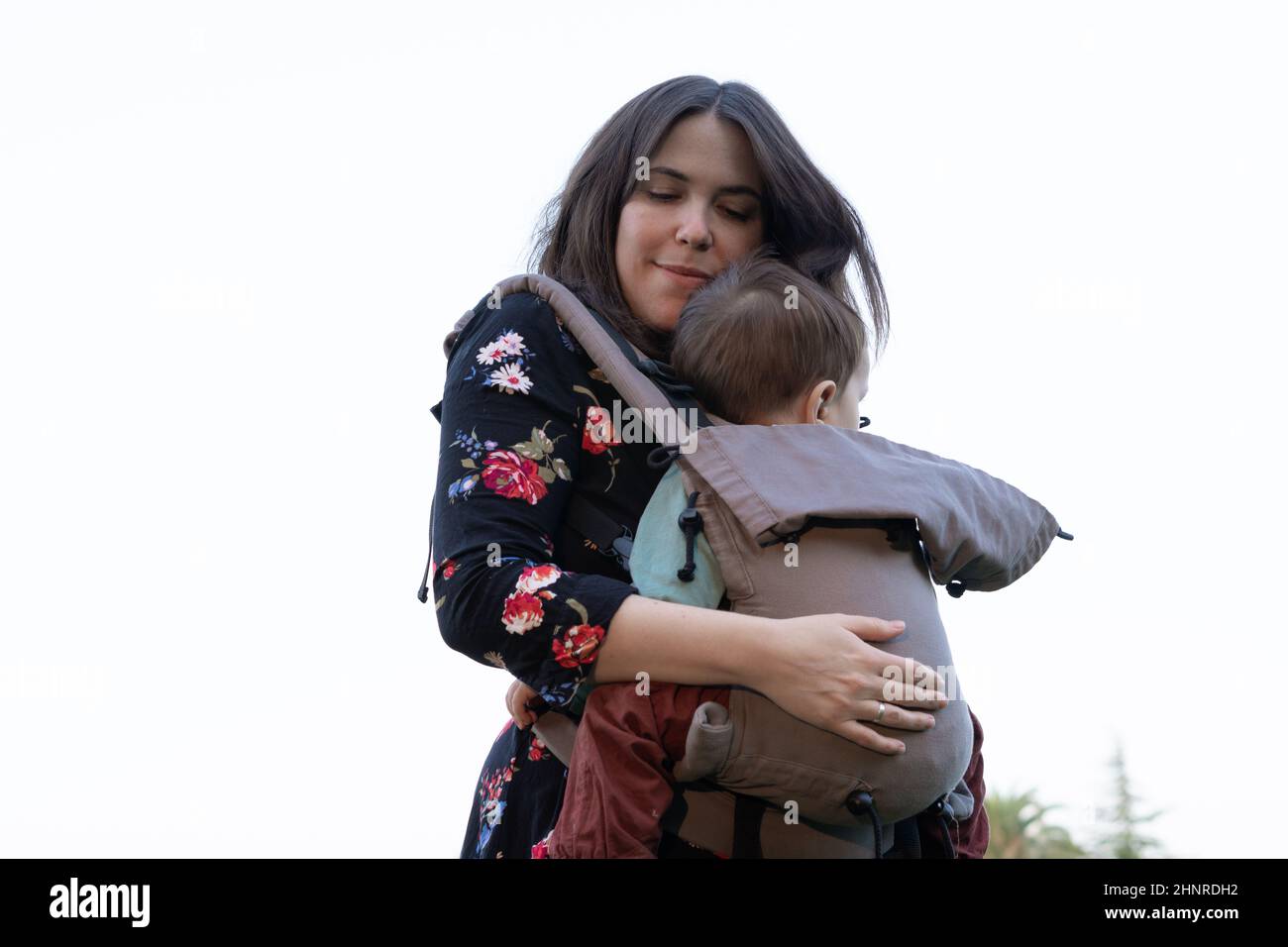 Jeune mère avec son enfant garçon sur le dos dans un porte-bébé ergonomique en nature automnale.Concept de mère active Banque D'Images