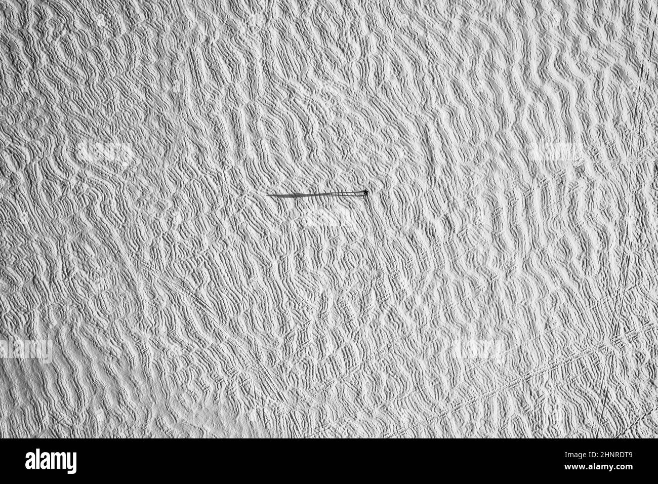 Vue aérienne d'un lac gelé recouvert de neige avec une minuscule silhouette et une ombre Banque D'Images