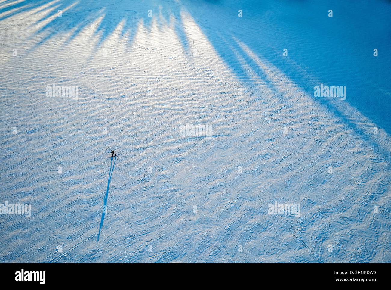 Petite figure et ombre d'un skieur solitaire sur un lac gelé, Maine Banque D'Images