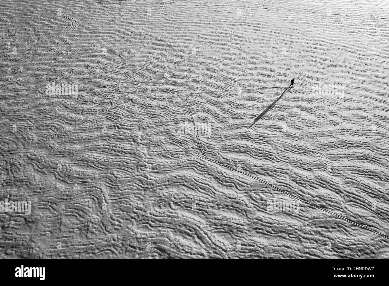 Vue aérienne d'un petit skieur solitaire sur un lac texturé recouvert de neige gelée Banque D'Images