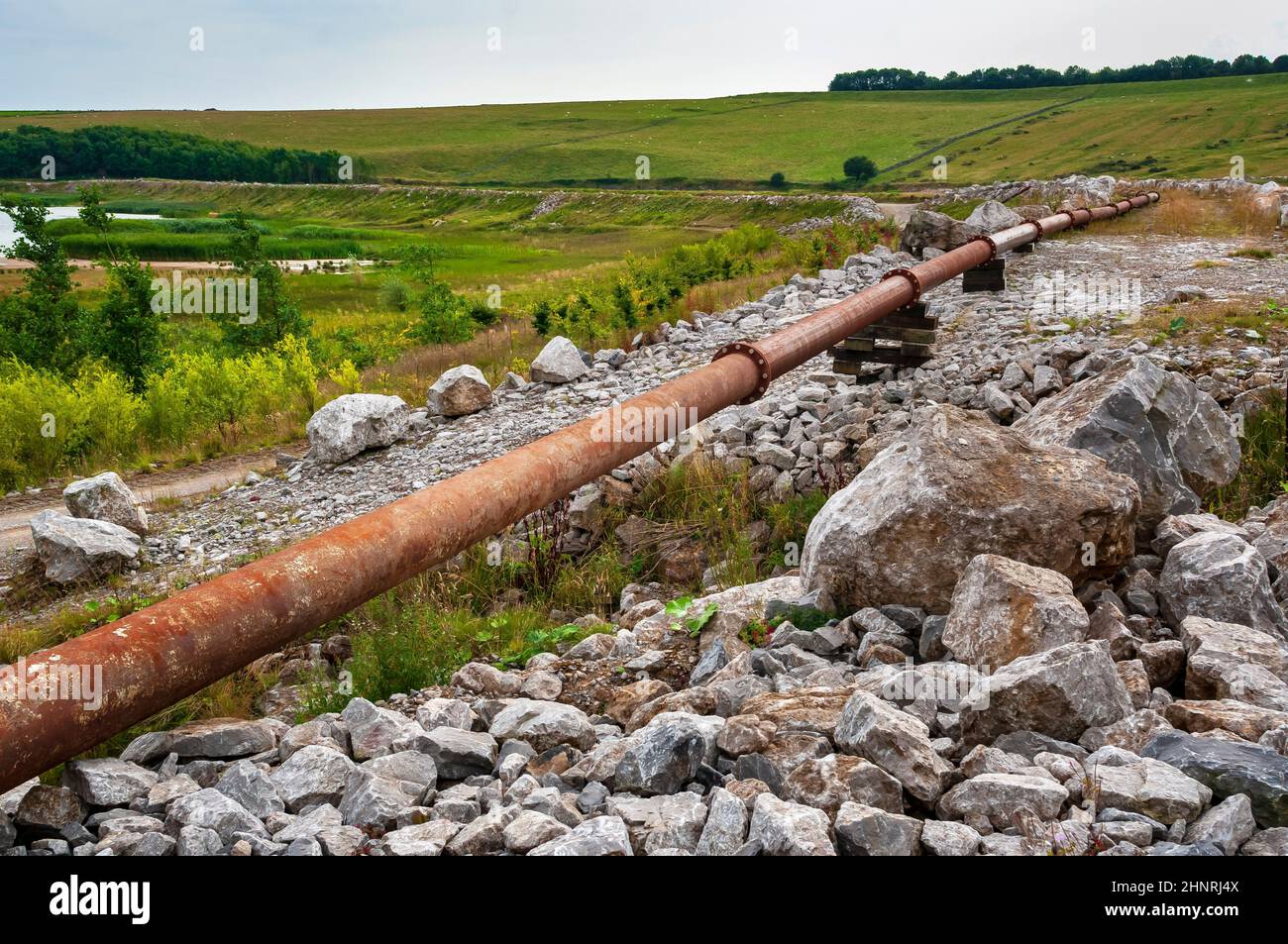 La grande lagune de décantation à Cavendish Mill est située près de Stoney Middleton, avec un pipeline en acier rouillé le long du bord. Banque D'Images