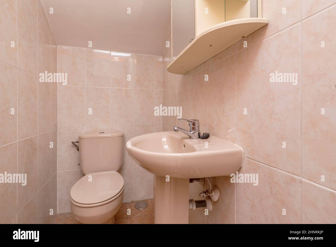 Petit lavabo aux tons roses sous un escalier Banque D'Images