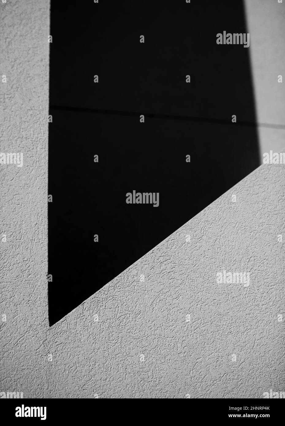conception abstraite des ombres sur le mur extérieur gris blanc du bâtiment créant des formes géométriques dans des angles noir et blanc et des lignes de fond vertical Banque D'Images