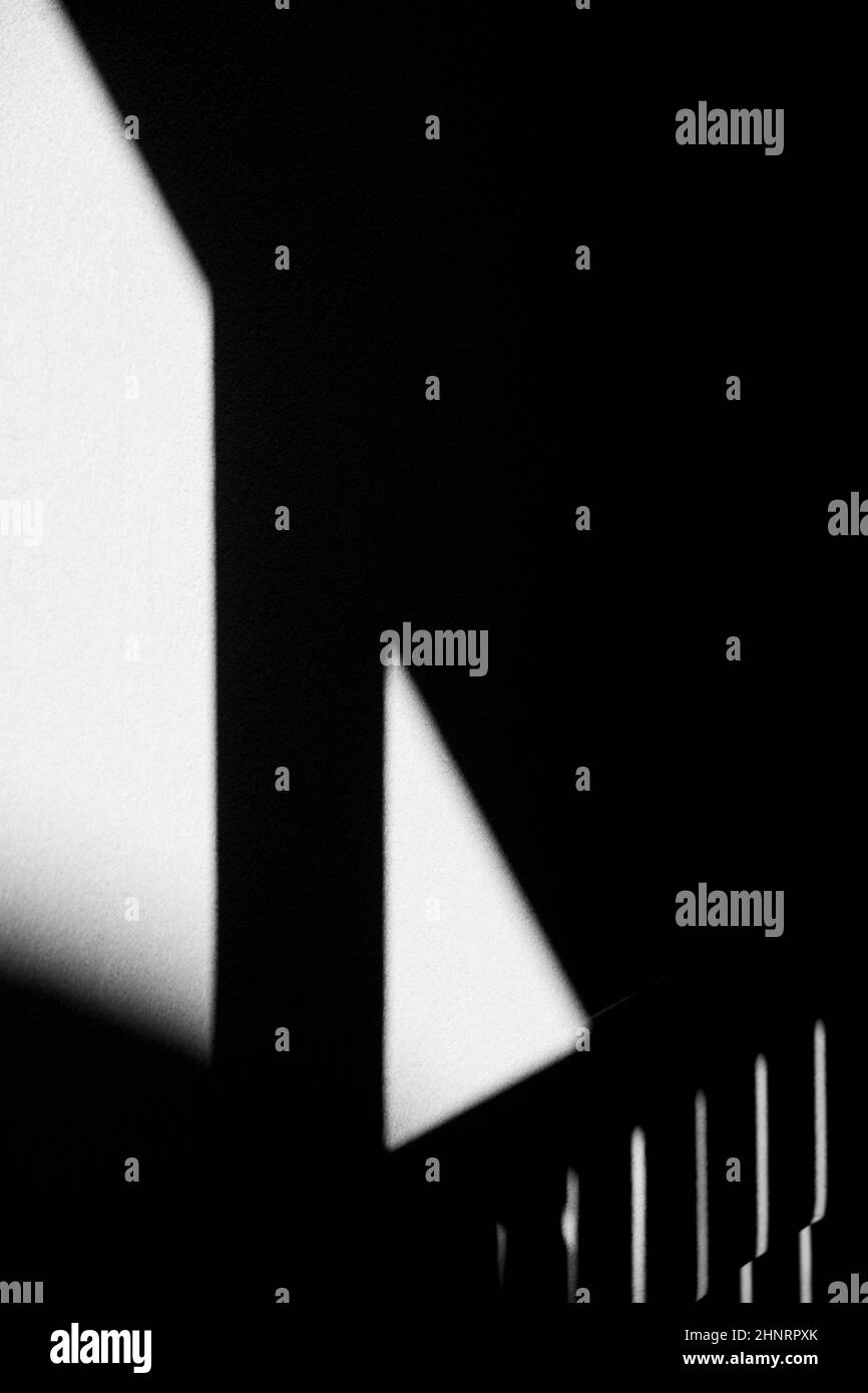 Ombre noire de l'escalier et de la rambarde coulées sur du ciment blanc ou un mur en béton créant des formes géométriques rectangle et triangle avec des lignes diagonales Banque D'Images