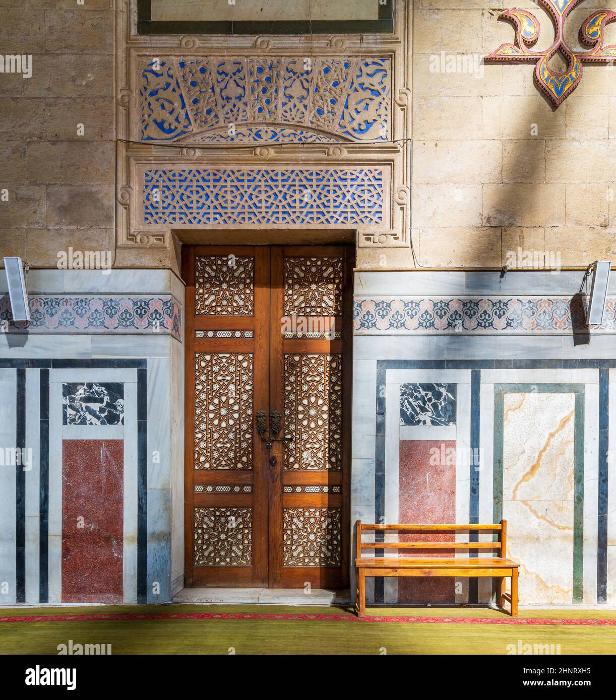 Porte en bois ornementale, murs décorés de mosaïques, banc en bois et sol éclairé par des poutres apparentes, mosquée Al Rifai, le Caire, Égypte Banque D'Images