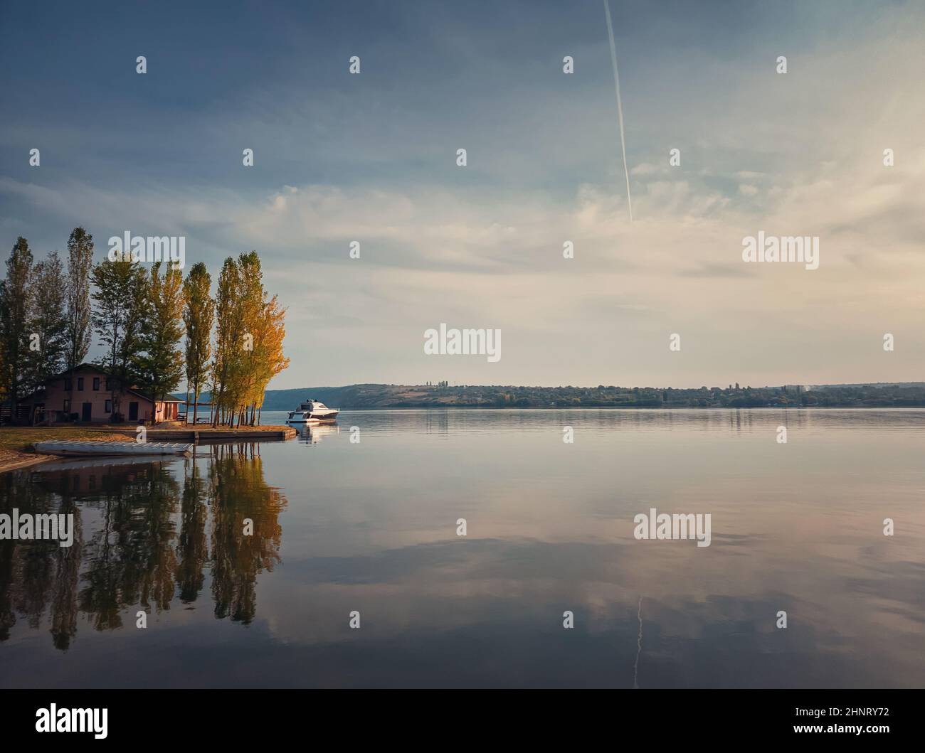 Vue panoramique avec une maison sur la rive de la rivière Nistru et un yacht flottant.Paysage de la saison d'automne, arbres colorés et ciel magnifique réfléchi Banque D'Images