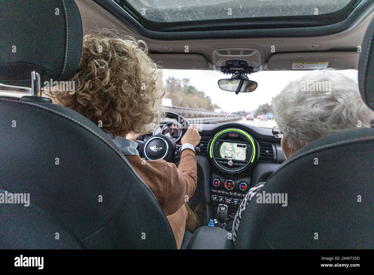 mère voiture de conduite avec grand-mère assis comme sozius dans la petite voiture. Ils conduisent sur l'autoroute par mauvais temps Banque D'Images