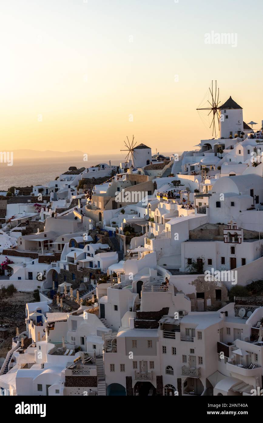 Maisons et moulins à vent blanchis à la chaux à Oia dans les rayons chauds du coucher du soleil sur l'île de Santorini. Grèce Banque D'Images