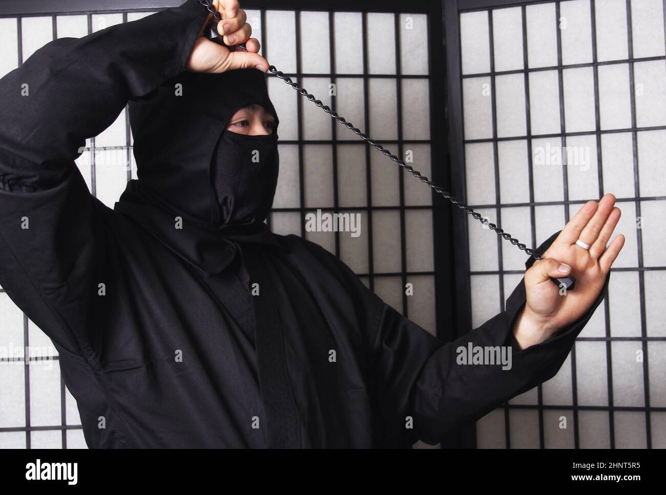 Homme asiatique portant un costume de ninja et tenant des armes de ninja Banque D'Images