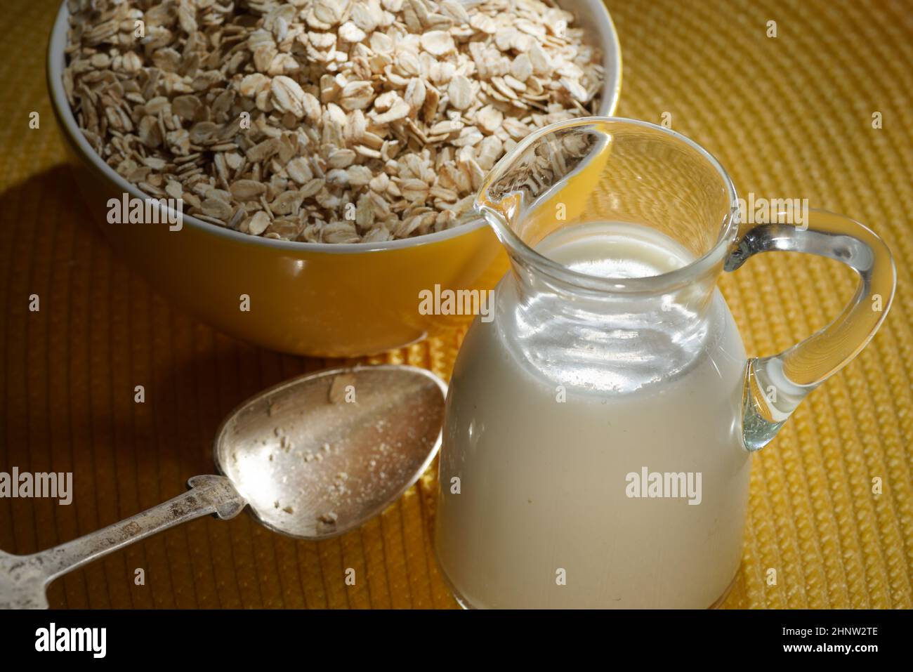 Flocons d'avoine dans un bol en bois, flocons d'avoine et tasse de lait sur la table. Une alimentation saine Banque D'Images