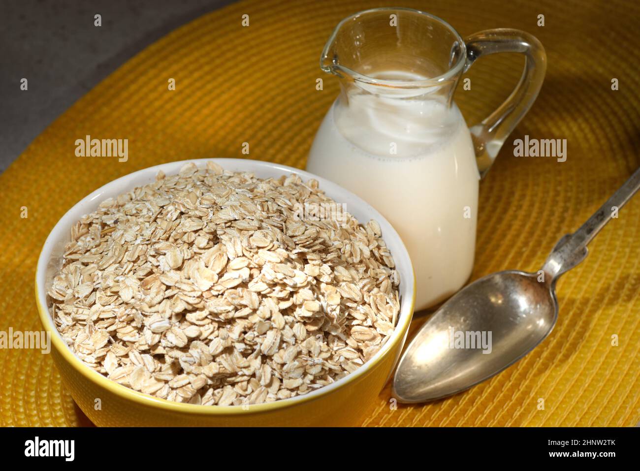 Flocons d'avoine dans un bol en bois, flocons d'avoine et tasse de lait sur la table. Une alimentation saine Banque D'Images