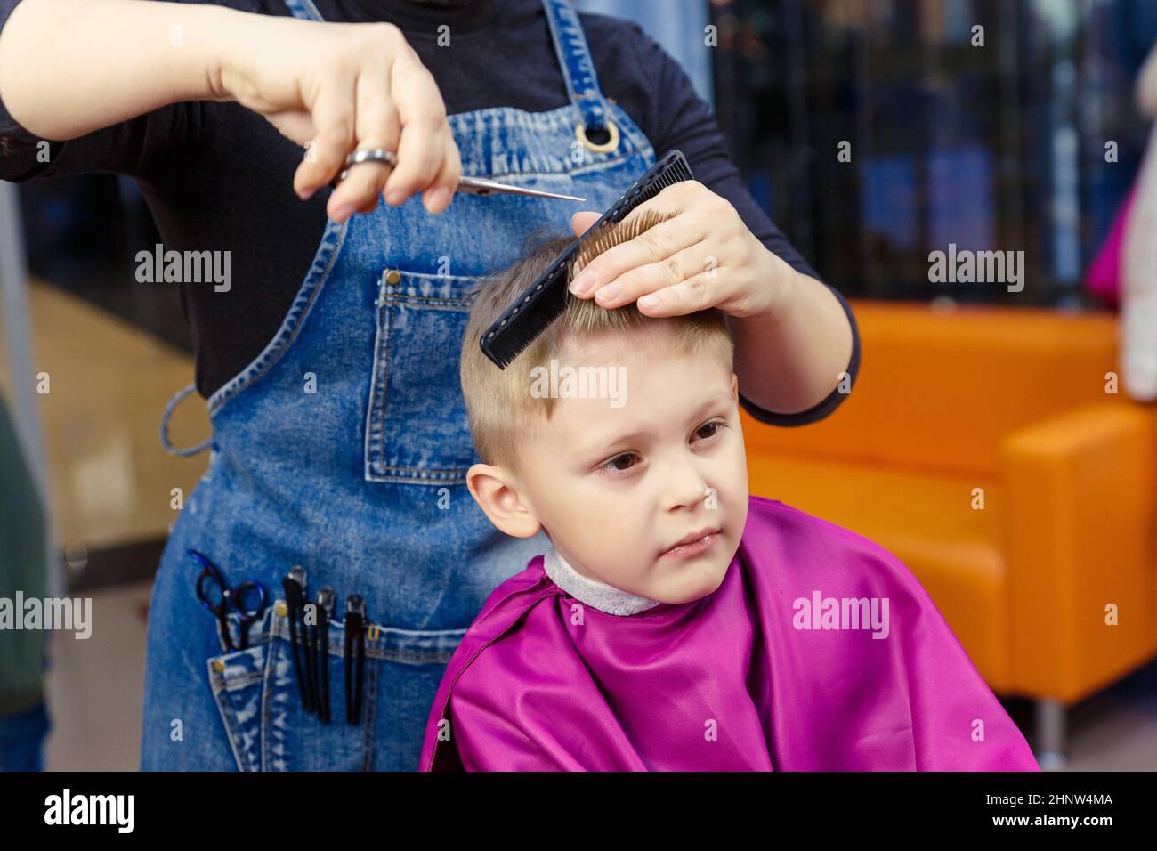 Le concept d'un coiffeur pour enfants. Le garçon est dans un salon de coiffure pour enfants et coupe ses cheveux dans un salon de coiffure pour enfants. Banque D'Images