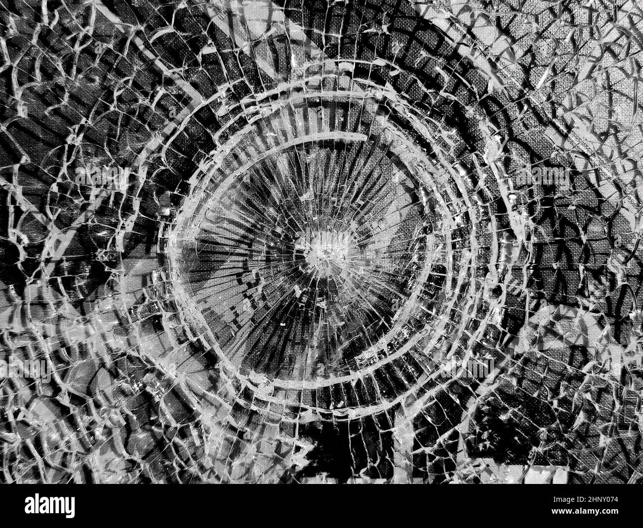 Verre cassé. Trou rond avec fissures radiales dans la vitre. Fissures blanches rondes dans le verre sur fond noir Banque D'Images