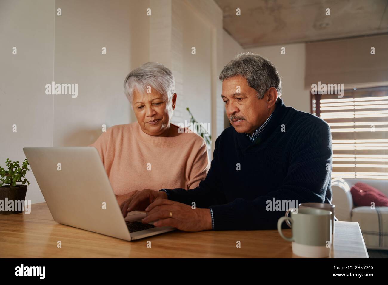 Couple multiethnique âgé recherchant des destinations de vacances sur leur ordinateur portable tout en étant assis à la maison. Retraité et heureux. Banque D'Images