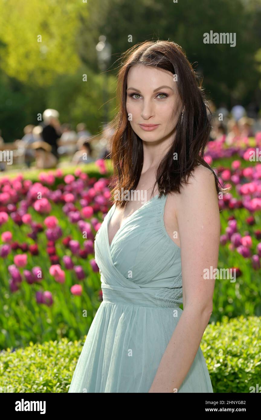 Une belle jeune femme russe dans un parc au premier soleil de printemps chaud avec une robe turquoise clair. Banque D'Images