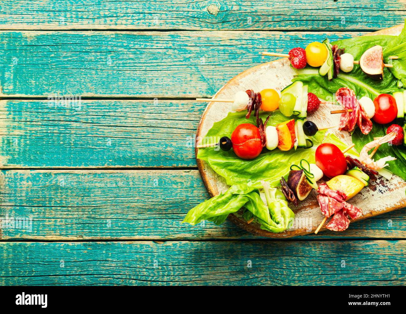 Apéritif de crevettes, jamon, fruits et légumes sur brochettes en bois Banque D'Images