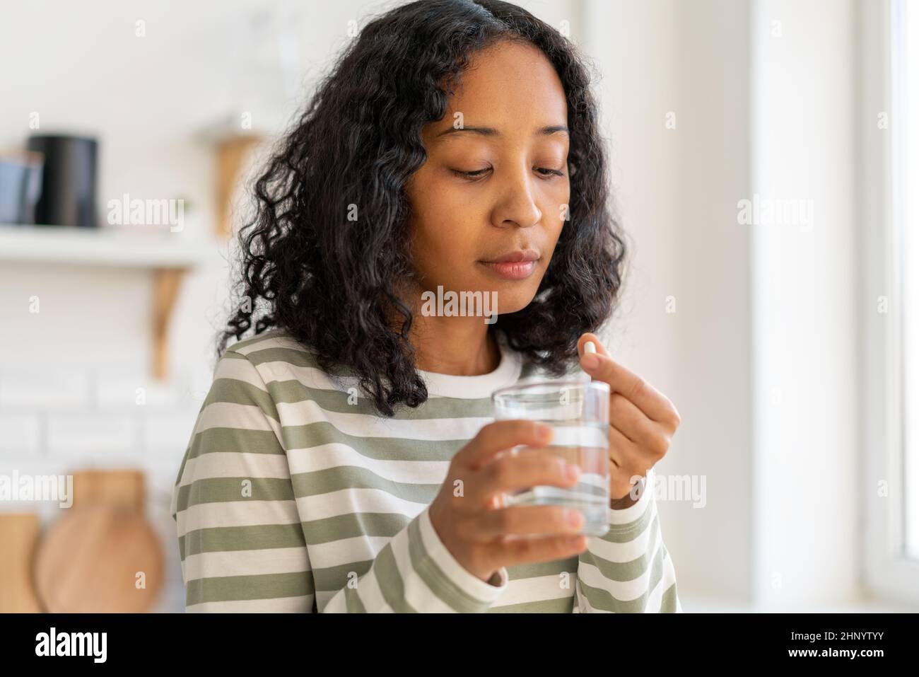 African-american femme lavant la pilule avec le verre d'eau.traitement de remède de supplément sain Banque D'Images