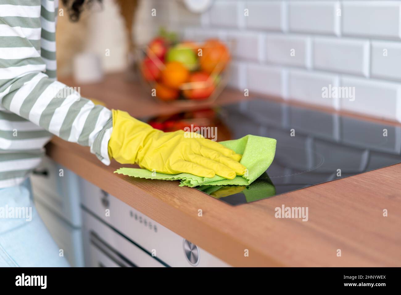 Table de cuisson à induction, sans visage, avec gants jaunes et débarbouillette verte Banque D'Images