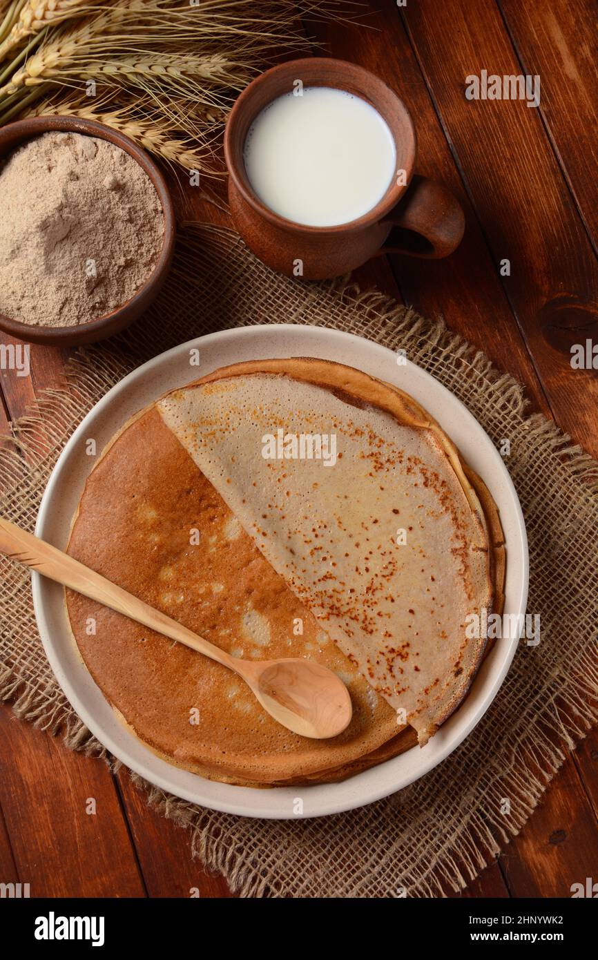 Des galettes de sarrasin traditionnelles bretons sur une table avec de la farine, une plante de blé et du lait Banque D'Images