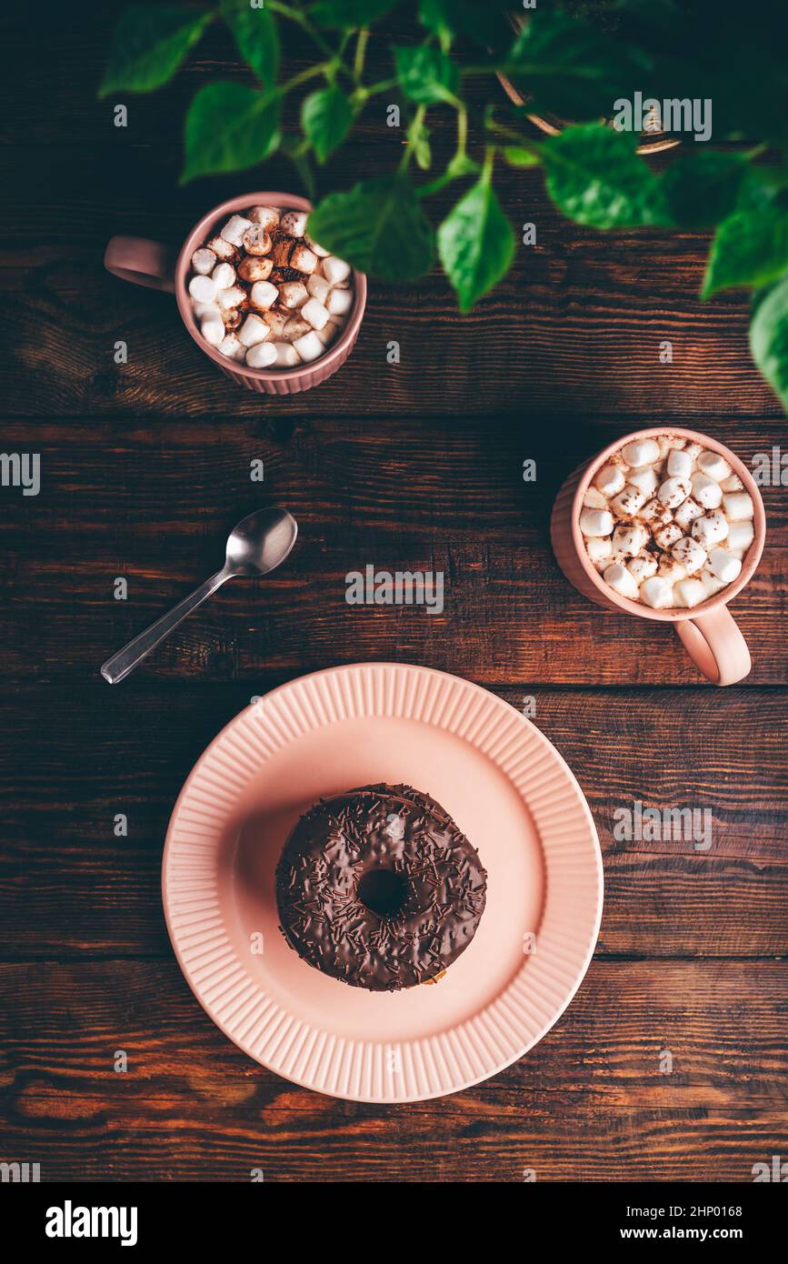 Pile de beignets au chocolat maison et de tasses de chocolat chaud avec Marshmallow sur une surface en bois rustique.Vue de dessus Banque D'Images