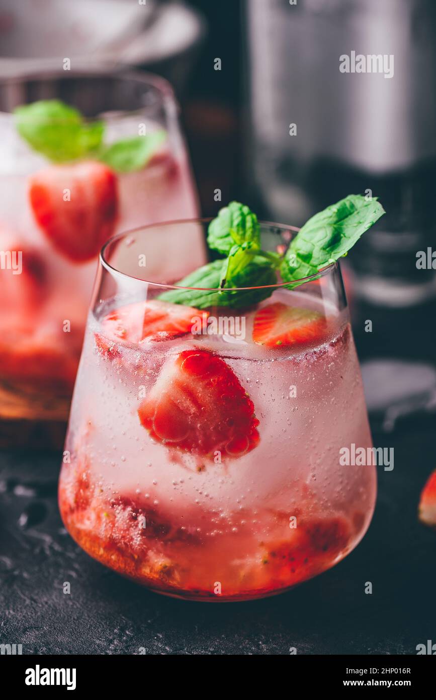 Deux verres de cocktail avec des fraises fraîches et congelées, du gin et du tonique Banque D'Images