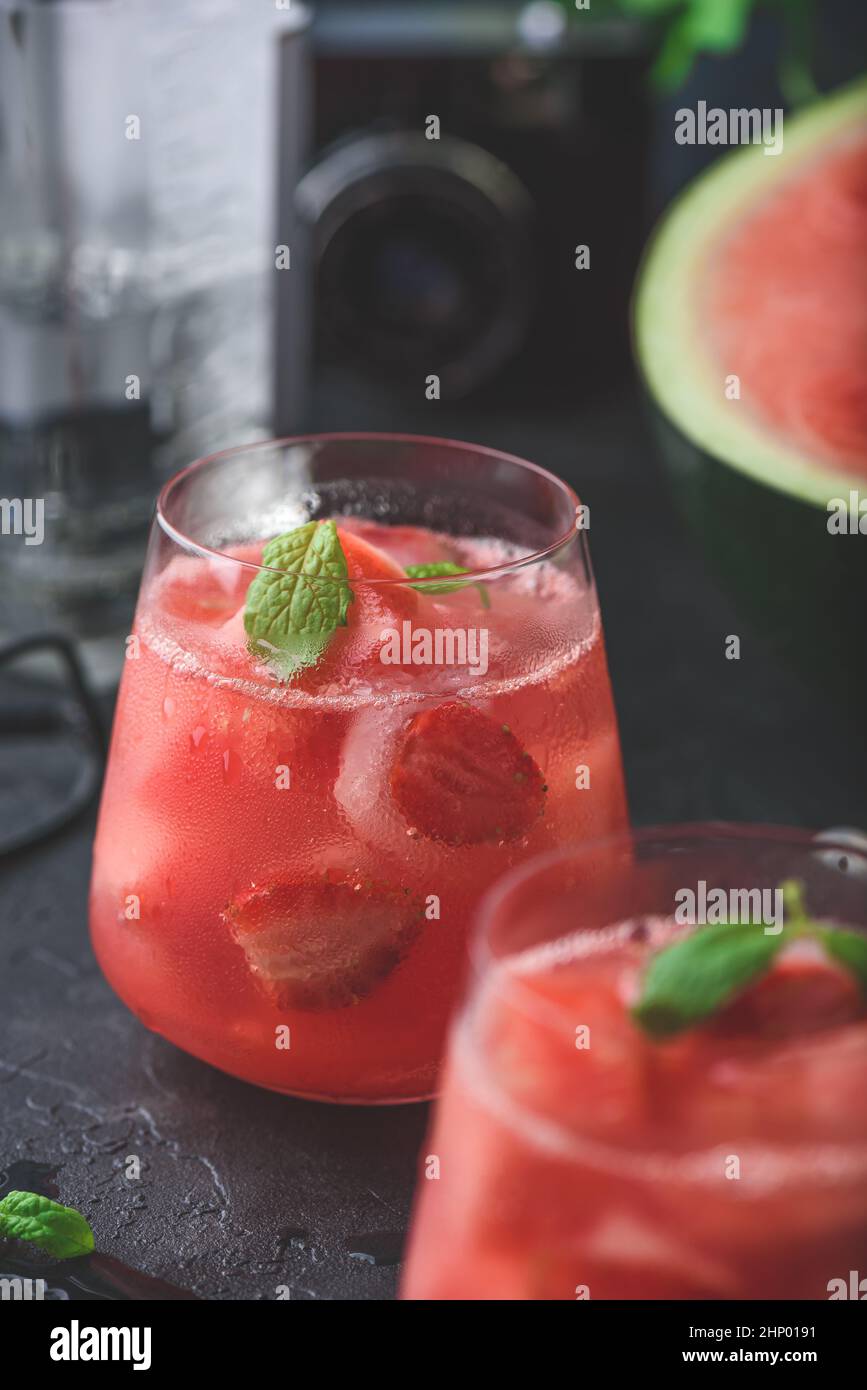 Cocktail frais avec garniture de pastèque, fraise et menthe sur fond de béton foncé Banque D'Images