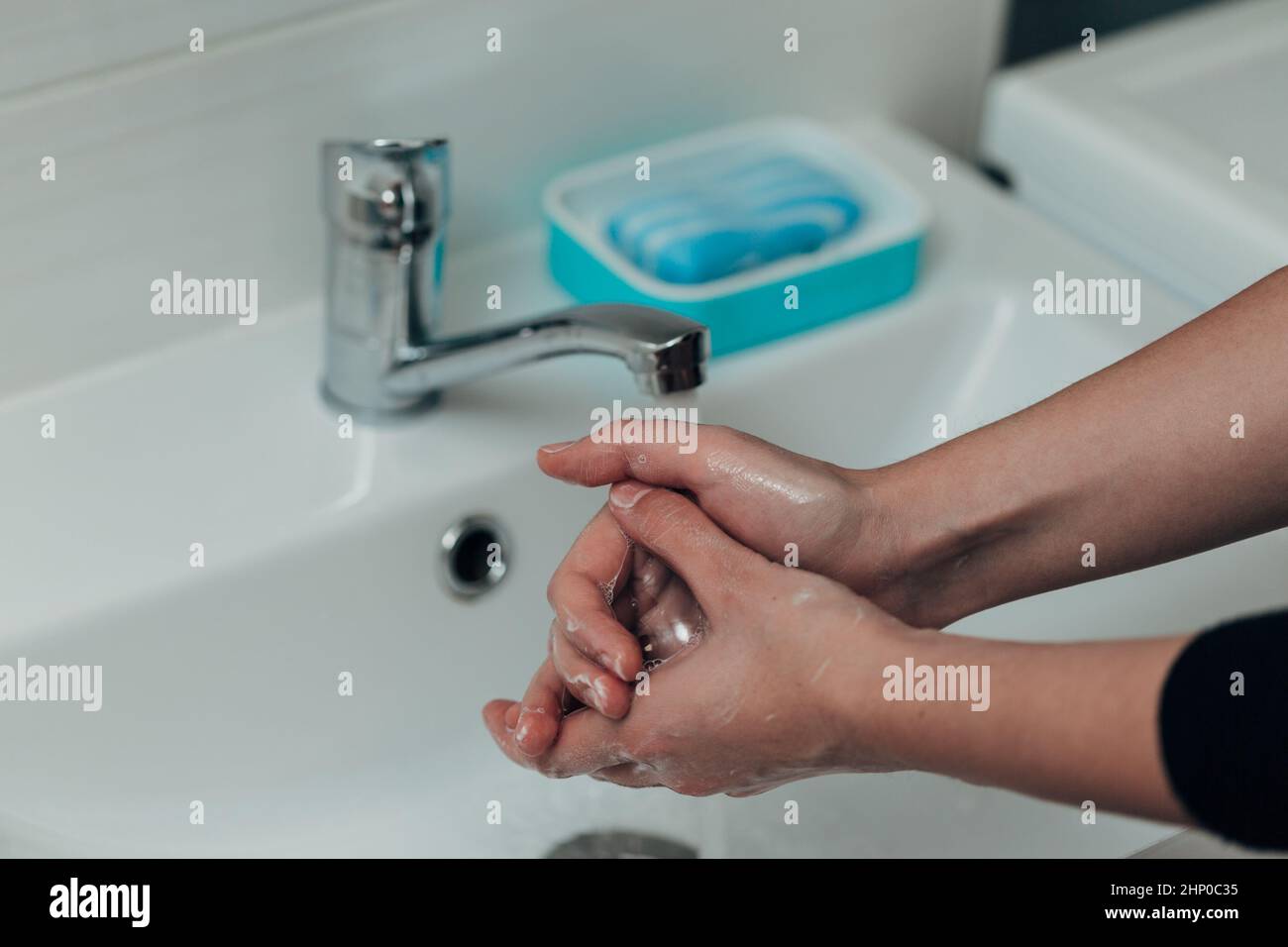 La fille se lave les mains pour éviter l'infection par le virus COVID