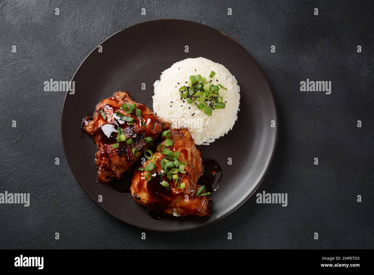 Cuisses de poulet marinées et cuites dans une sauce adobo.Plat philippin national.Adobo avec riz gros plan sur une assiette. Banque D'Images